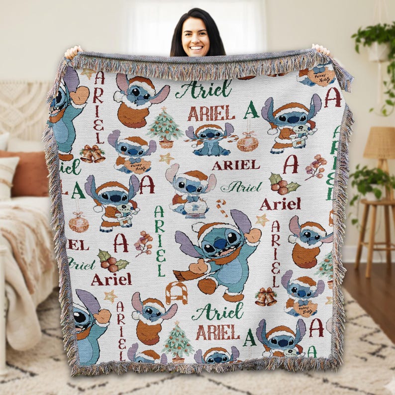 A woman is holding up a blanket with a repeating pattern of Ariel characters from the Disney movie Lilo and Stitch.