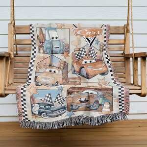 A blanket featuring various cars from the Disney Pixar movie Cars, including a race car, a truck, and a car with a checkered flag.
