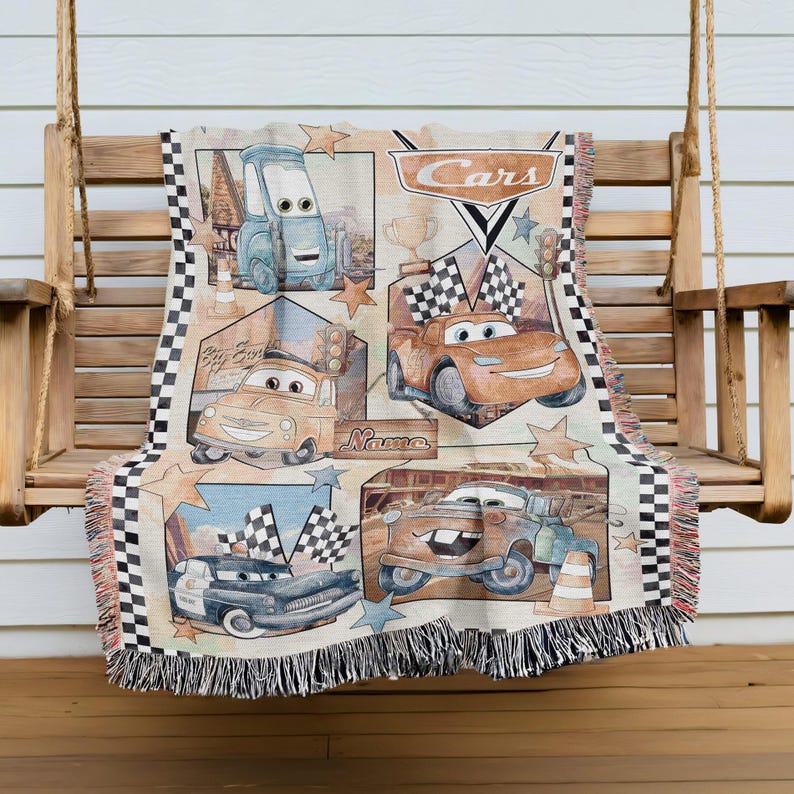 A blanket featuring various cars from the Disney Pixar movie Cars, including a race car, a truck, and a car with a checkered flag.