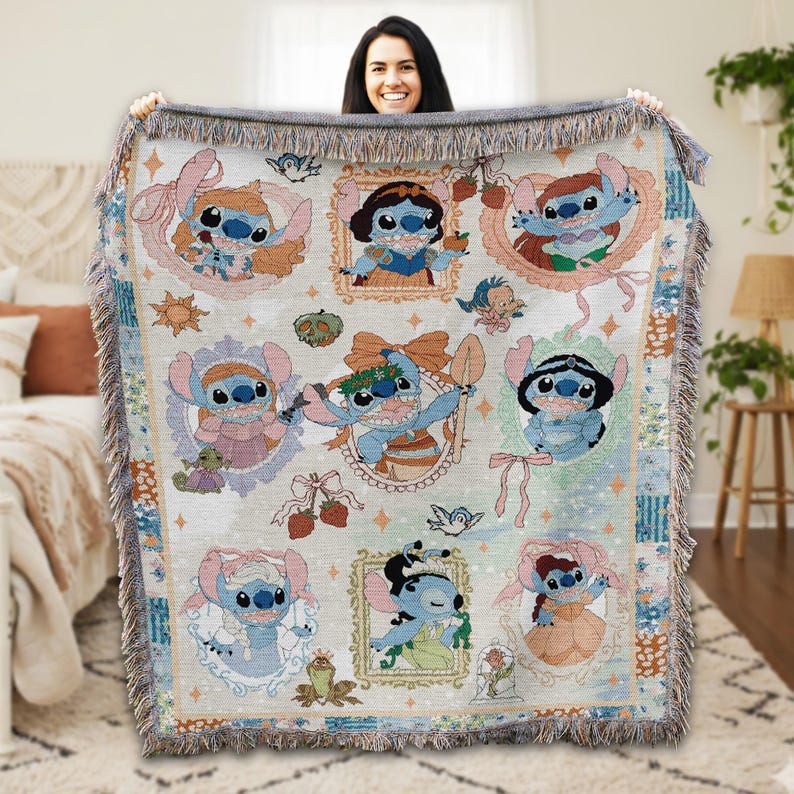 A woman is holding up a colorful, embroidered blanket featuring various characters from the Disney movie "Strawberry Fields".
