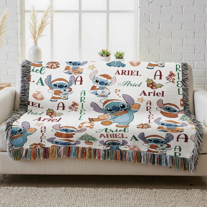A colorful throw blanket with the character Ariel from the Disney movie Lilo and Stitch printed on it, placed on a couch in a room with a window.