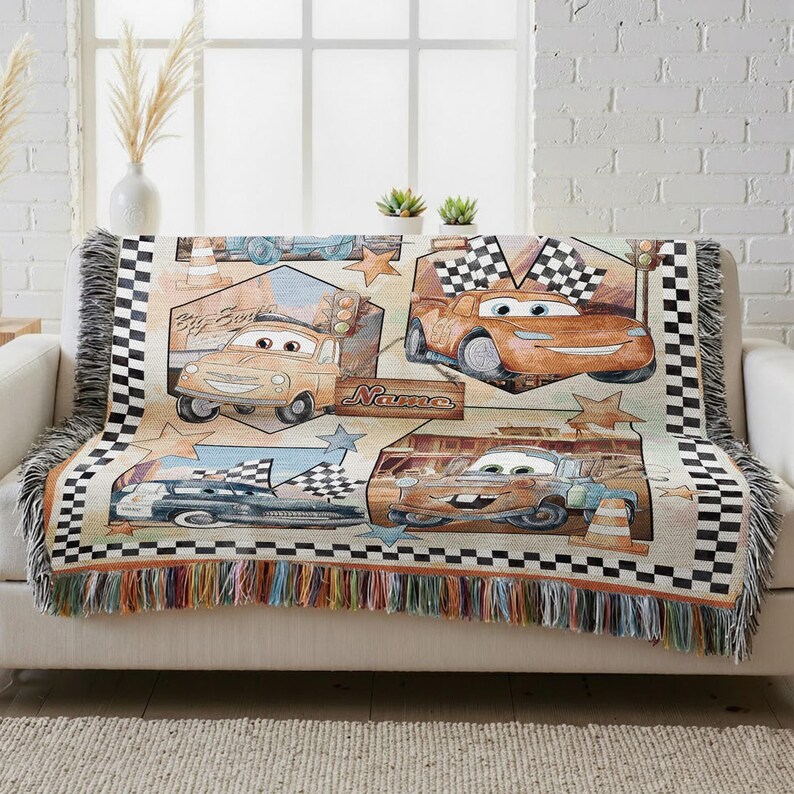 A colorful throw blanket with a Cars-themed design, featuring various race cars and racing elements.