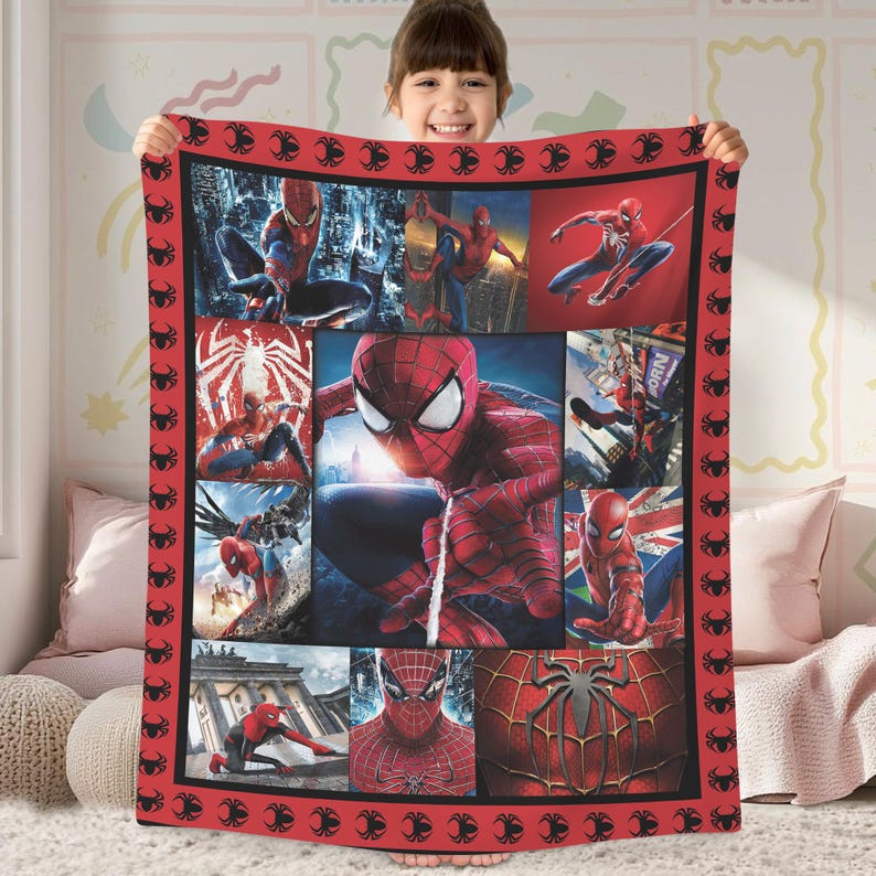 A young girl is holding up a large quilt featuring various images of Spider-Man characters.