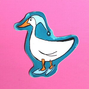 May include: A whimsical illustration of a white duck wearing a light blue nightcap and matching slippers. The duck has an orange beak and feet, outlined in black, set against a teal blue background with a pink backdrop.