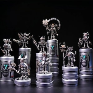 May include: A collection of silver-colored robot figurines, each uniquely designed and posed. They stand atop cylindrical containers with a question mark symbol. The robots have various accessories, including wings, weapons, and circular headpieces. The background is black.
