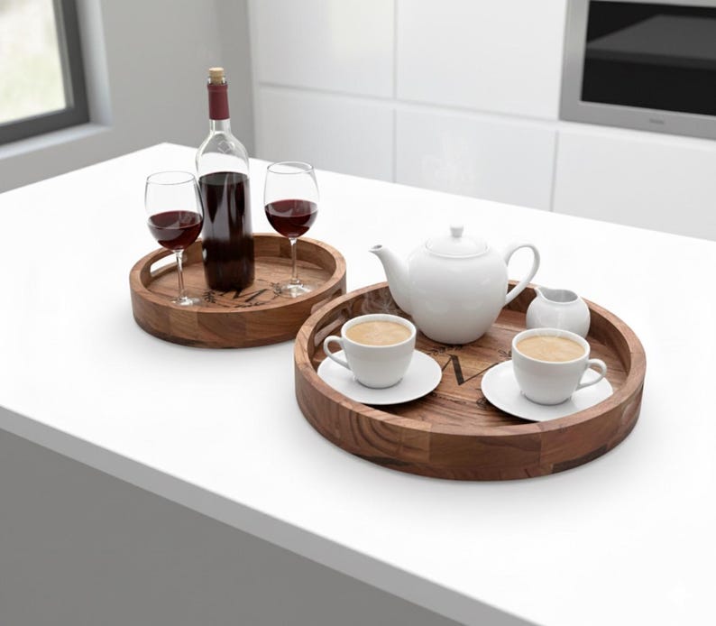 Puede incluir: Dos bandejas de madera. Una contiene una botella de vino tinto y dos copas de vino. La otra tiene una tetera blanca, dos tazas de caf&eacute; y una jarrita de crema. Las bandejas est&aacute;n sobre una superficie blanca.