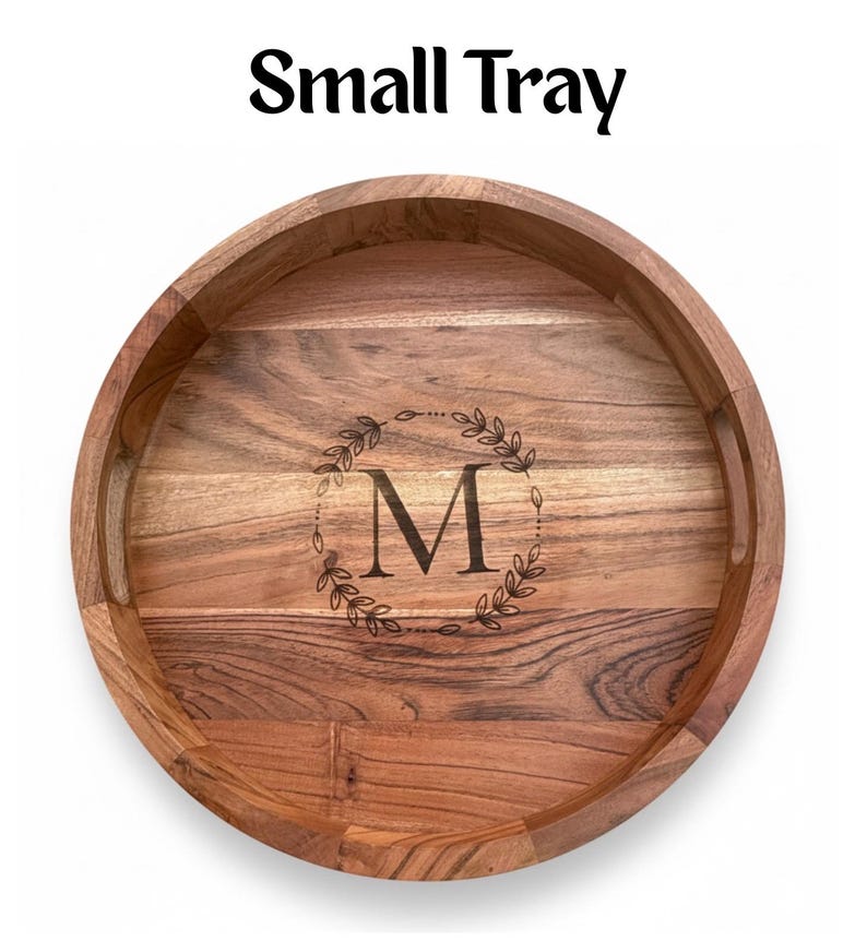 Puede incluir: Una bandeja redonda de madera con un acabado de vetas naturales. La bandeja tiene un borde elevado y dos asas. El centro presenta una corona decorativa alrededor de la letra "M". El texto "Small Tray" est&aacute; en la parte superior.