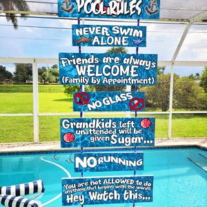 May include: A set of blue and white pool rules signs with phrases like "Never Swim Alone" and "No Running." The signs are suspended above a swimming pool with a blue water surface.