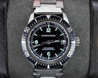 Reloj de buceo Kingsmark vintage, fabricado en Suiza, con esfera negra, fecha y brazalete de acero inoxidable.