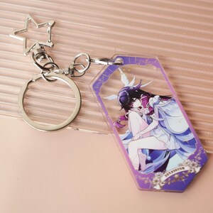 May include: A clear acrylic keychain with a silver metal clasp and a star-shaped charm. The keychain features a colorful anime-style illustration of two figures in a romantic embrace, with purple and white accents. The keychain is a decorative accessory.