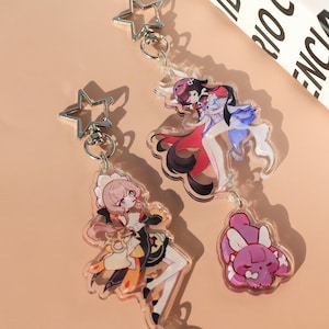 May include: Clear acrylic keychains featuring anime-style characters. One keychain has a pink-haired character in a maid outfit, another has a character in a red and blue outfit, and the last one is a pink bunny. Each keychain has a silver star-shaped clasp.