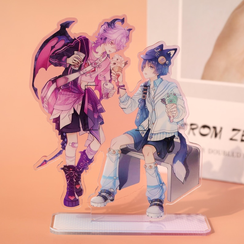 May include: Acrylic stand featuring two anime-style characters. One character has purple hair and wings, holding a drink and ice cream. The other character has blue hair and cat ears, also holding ice cream. The stand has a clear base.