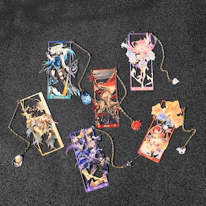 Könnte beinhalten: Eine Sammlung von sechs Lesezeichen mit Anime-Charakteren. Jedes Lesezeichen zeigt ein einzigartiges Charakterdesign mit leuchtenden Farben und aufwendigen Details. Sie sind rechteckig mit einer Kette und einem Anhänger versehen. Die Namen "Feixiao", "Myde" und "Herta" sind sichtbar.