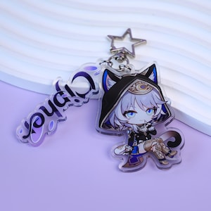 May include: A clear acrylic keychain featuring a cartoon character with cat ears, wearing a black hooded outfit with gold accents. The keychain includes a star-shaped clasp and a separate charm with the word "Cypher" in purple.