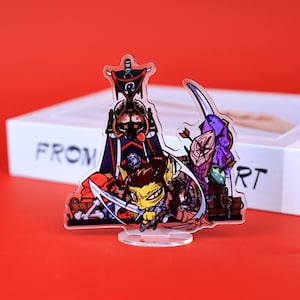 Könnte beinhalten: Klare Acrylfigur mit einer Cartoon-Figur eines Goblins mit einem Schwert, vor dem Hintergrund anderer Cartoon-Charaktere und -Objekte. Die Figur steht auf einem transparenten Ständer, mit dem Wort "FROM" auf einer weißen Box im Hintergrund.