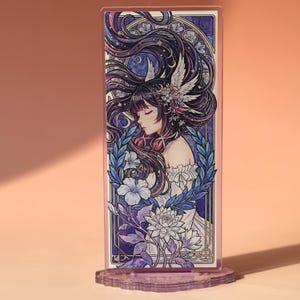 May include: A decorative acrylic stand featuring a detailed illustration of a woman with long, flowing hair adorned with flowers and celestial elements. The artwork is framed with a blue and purple border, and the stand has a decorative base.
