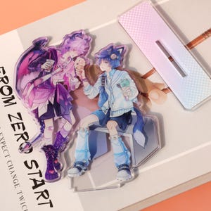May include: Acrylic standees featuring anime-style characters with ice cream and drinks. One character has purple hair and wings, the other has blue hair and fox ears. The text "FROM ZERO START" is visible.