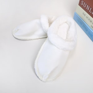 Puede incluir: Un par de zapatillas blancas y esponjosas con un forro suave y afelpado. Las zapatillas tienen un diseño sencillo, ideal para uso en interiores. El ribete esponjoso añade comodidad y estilo. Estas zapatillas están diseñadas para la relajación.