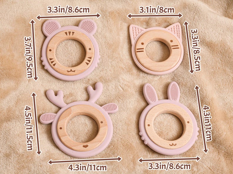 May include: Four baby teething toys in the shape of a bear, cat, deer, and bunny. Each toy has a light pink silicone exterior and a natural wood ring. The toys measure between 3.1 to 4.5 inches in length.