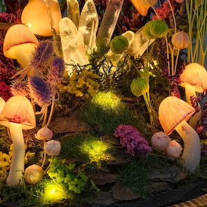 May include: A fantasy scene with illuminated mushroom lights, crystals, and flowers. The mushrooms have orange-red caps and white stems. The scene includes purple, yellow, and green foliage, creating a magical ambiance. The crystals are clear.