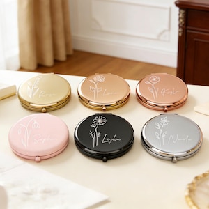 以下が含まれることがあります： 金、ブロンズ、ローズゴールド、ピンク、黒、シルバーの6色のパーソナライズされたコンパクトミラー。各ミラーには花の模様とエレガントなスクリプトで名前が刻まれています。コンパクトは丸く、ヒンジ付きの留め具が付いています。