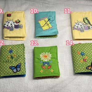 May include: A collection of six small, embroidered needle cases. The cases feature various designs, including a spool of thread, a bird, butterflies, and floral patterns. The cases are in shades of yellow, teal, and green, with polka dots and detailed stitching.