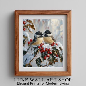 May include: A framed print featuring two small birds perched on a snow-covered holly branch with red berries. The birds have black and white markings with tan chests. The frame is made of wood.