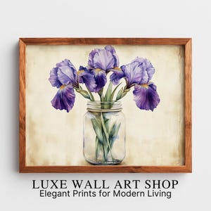 May include: Watercolor print of purple irises in a glass jar, set in a wooden frame. The flowers have detailed petals and green stems. The background is a soft, off-white color. Text at the bottom reads: LUXE WALL ART SHOP, Elegant Prints for Modern Living.