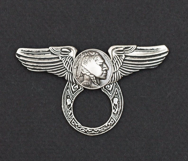 May include: Silver ring with a 1937 Buffalo nickel coin design and wings on either side. The ring is open and can be used as a key chain or a bottle opener.