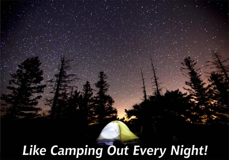 May include: A yellow and white camping tent set up in a forest under a night sky full of stars.