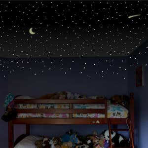Puede incluir: Una litera de madera con un colch&oacute;n de estampado blanco y colorido y un colch&oacute;n de estampado blanco y gris en la litera inferior. La habitaci&oacute;n tiene una pared azul oscuro con estrellas que brillan en la oscuridad y una luna creciente en el techo.