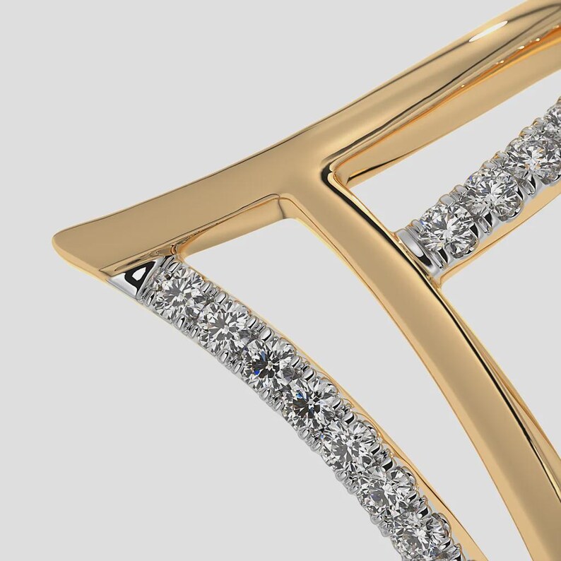 May include: Close-up of a gold-toned pendant with a geometric design. The pendant features a series of sparkling, round-cut diamonds set in a curved channel. The gold has a polished finish, and the diamonds are set in a silver-colored metal.