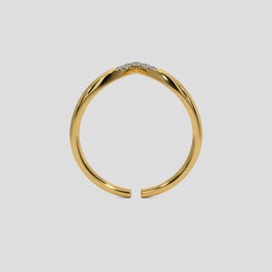 May include: A gold-colored ring with a V-shaped design at the top, adorned with small, sparkling stones. The ring has a smooth, polished finish and an open design. The ring is set against a light gray background.