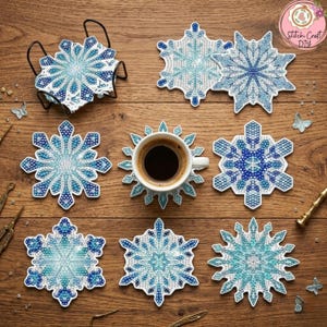 Può includere: Una collezione di sottobicchieri a forma di fiocco di neve nei toni del blu e del bianco, disposti su una superficie di legno. Una tazza da caffè bianca con liquido scuro poggia su un sottobicchiere. Farfalle e strumenti decorativi sono sparsi.