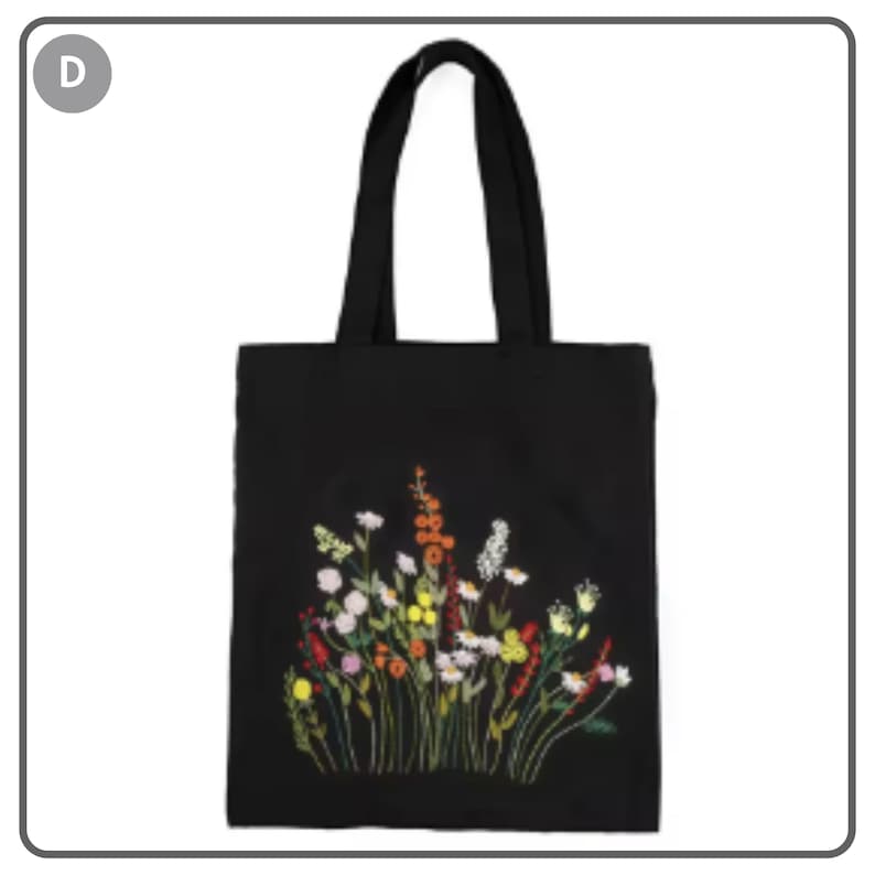 Puede incluir: Bolso tote negro con un dise&ntilde;o de bordado floral colorido. Las flores bordadas incluyen flores blancas, amarillas, rojas y rosas. El bolso tiene dos asas negras.