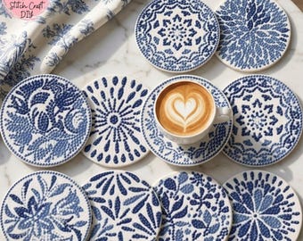 May include: A set of blue and white ceramic coasters featuring floral and geometric designs. A cup of coffee with latte art rests on one coaster. A patterned fabric in matching colours is in the background. The logo "Stitch Craft DIY" is visible.