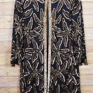 May include: A handmade wooden sign with the text "Welcome" in a playful font. The sign is painted white with a distressed finish, and features a decorative floral design in shades of pink and green. It measures approximately 12 inches wide.