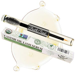 May include: A clear glass tube of Bath Rest Castor Oil Lash Serum with a black applicator brush and a fine-tipped applicator. The product is displayed with its white and green box, and a pool of oil.