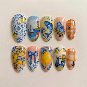 Puede incluir: Un conjunto de diez uñas artificiales pintadas con varios diseños. Los diseños incluyen un patrón de azulejos azules y blancos, un paisaje marino con un velero, un pez, un pájaro en una rama y un patrón de cuadros. Otras uñas presentan limones, lazos y un scooter.