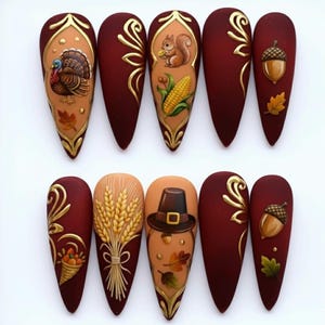 Könnte beinhalten: Ein Satz von zehn langen, mandelförmigen Kunstnägeln mit Thanksgiving-Motiven. Designs umfassen einen Truthahn, ein Eichhörnchen, Mais, Eicheln, Weizen, einen Pilgerhut und Herbstblätter. Die Nägel sind hauptsächlich weinrot mit goldenen und beigen Akzenten.