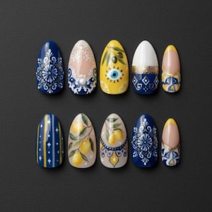 Puede incluir: Un conjunto de diez uñas postizas de forma ovalada con diversos diseños. Los diseños incluyen patrones florales azules y blancos, encaje, limones, un ojo turco y detalles dorados. Las uñas están dispuestas sobre un fondo negro.
