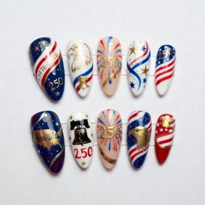 May include: A set of ten artificial nails with patriotic designs. Each nail features red, white, and blue colors, with stars, stripes, an eagle, and the number "250". Some nails also display the text "1776-2026".