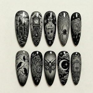 May include: A set of ten black, almond-shaped artificial nails with intricate, hand-painted gothic designs. Each nail features a different spooky illustration, including a haunted castle, spiderwebs, and a crescent moon.