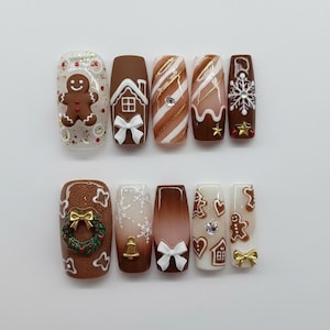 May include: A set of ten press-on nails with a festive gingerbread theme. Designs include gingerbread men, houses, snowflakes, and bows, in shades of brown, white, and gold. Some nails feature glitter and decorative accents for a holiday look.