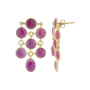 Op de afbeelding: Goudkleurige oorhangers met meerdere ronde, magenta gekleurde edelstenen. De oorbellen hebben een post-back sluiting en een trapsgewijs ontwerp. De edelstenen zijn gezet in een goudkleurig metalen frame.