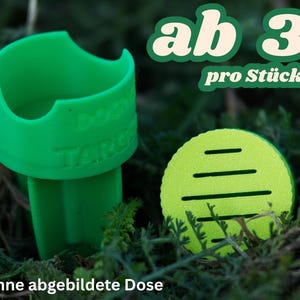 Può includere: Un porta snack per cani in plastica verde e uno snack rotondo verde lime. Il supporto ha il testo "DOG TARGET" ed è in un letto di fogliame verde. È visibile anche il testo "ab 3 € pro Stück".