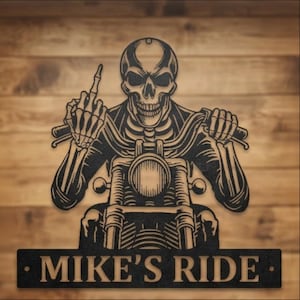 Puede incluir: Arte de pared de metal negro que representa un esqueleto en una motocicleta haciendo un gesto obsceno. El texto "MIKE'S RIDE" se muestra en una placa rectangular. Fondo de madera.