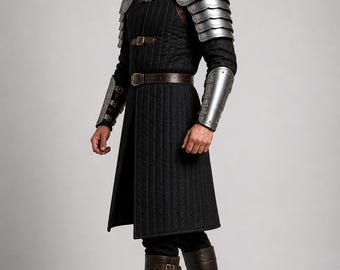 May include: A black quilted long-sleeved tunic with a high collar, worn with silver metal pauldrons and bracers, a brown leather belt, and dark brown leather boots with three buckles. The Medieval Store logo is visible in the top right corner.