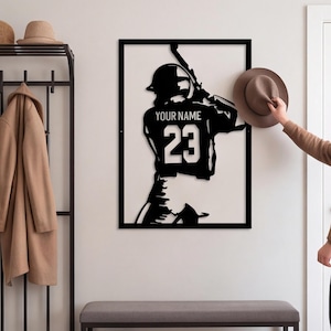 Op de afbeelding: Een rechthoekig zwart metalen wanddecoratie met het silhouet van een honkbalspeler in slagpositie. De speler draagt een shirt met de tekst YOUR NAME en het nummer 23 op de rug. Het ontwerp is omlijst met zwart metaal.