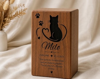 May include: A rectangular wooden pet urn featuring a laser-engraved silhouette of a cat, two paw prints, and a heart. The text reads: Milo, 15.06.1990, 02.11.2023, and the inscription: You were my favorite hello and my hardest goodbye. Thank you for a lifetime of love.
